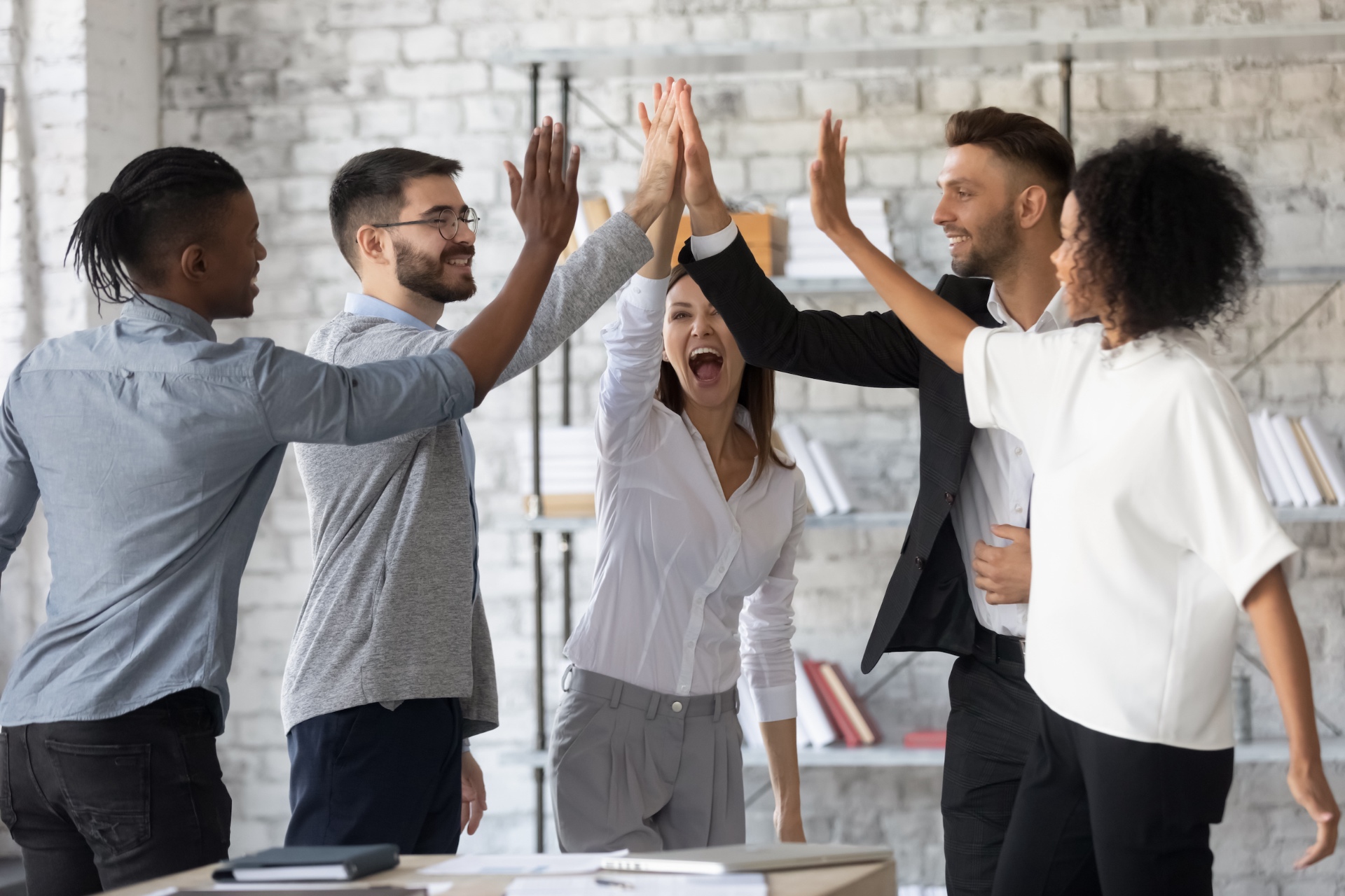 Equipo celebrando un resultado conjunto con las manos en alto